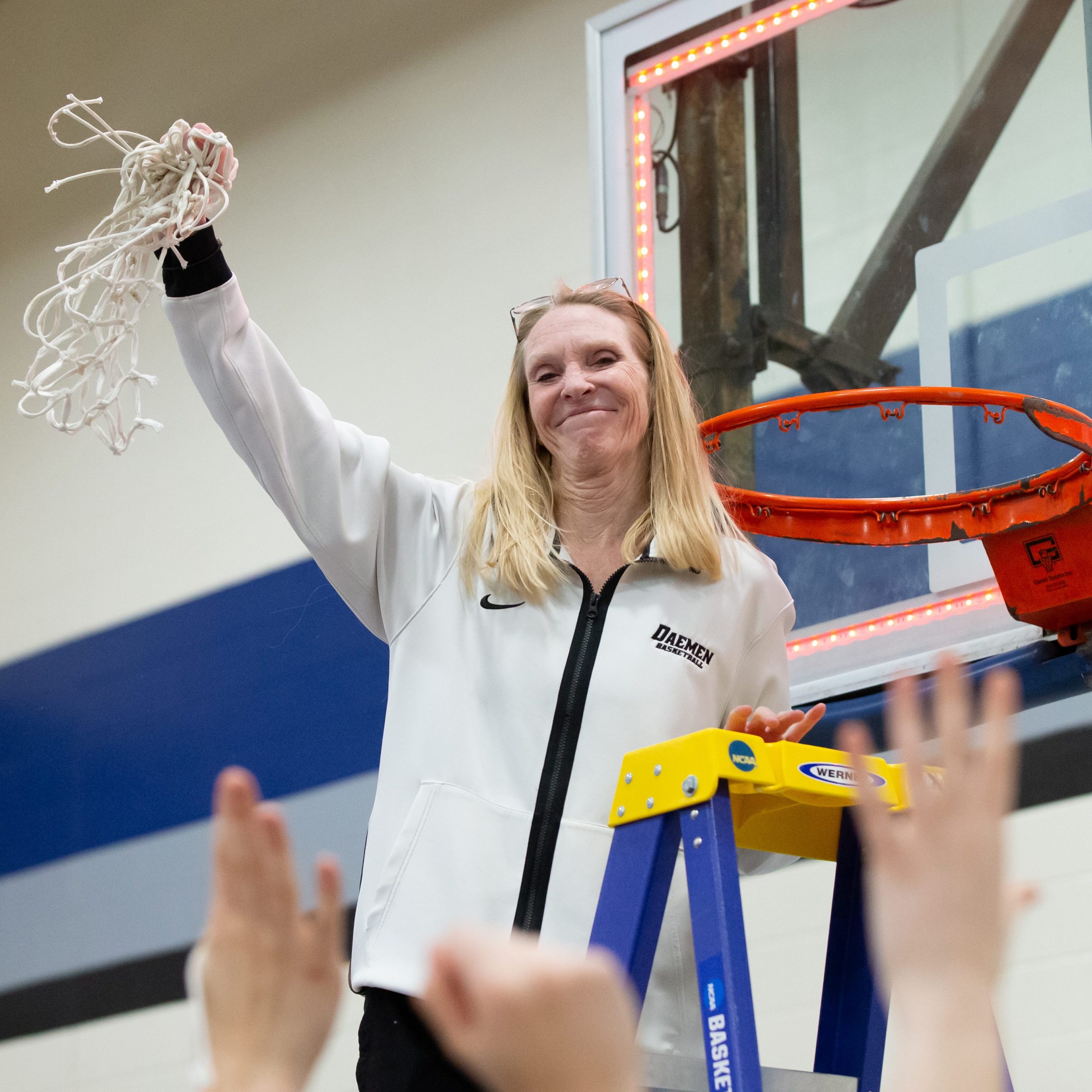 Womens basketball coach cutting down net after win