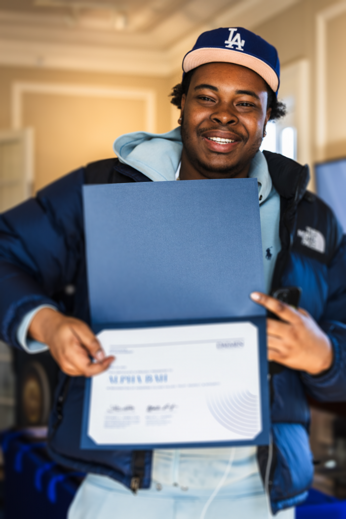 Student smiling holding and pointing to a certificate