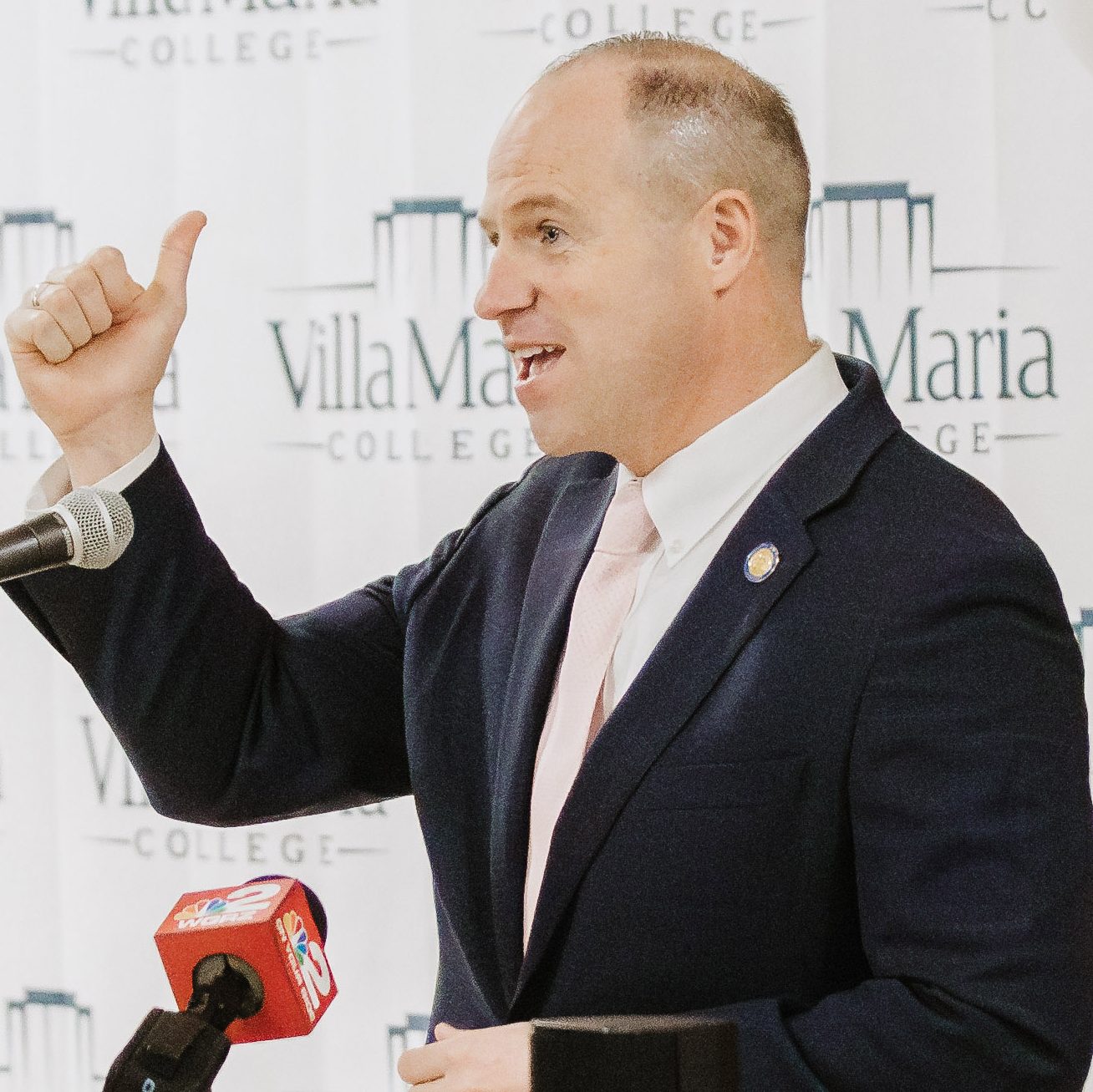 New York State Senator Tim Kennedy standing behind a podium with his right thumb up