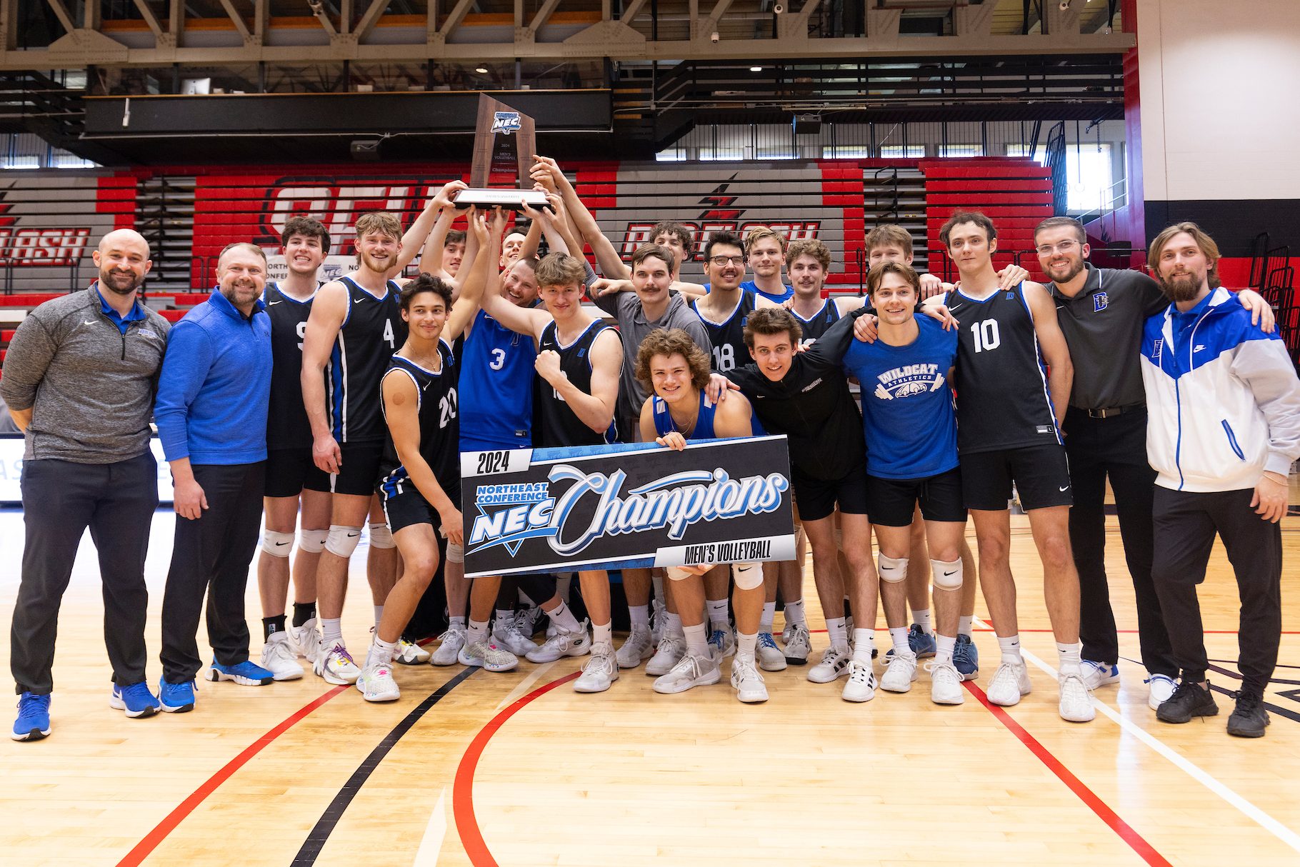 Mens volleyball team holding championship trophy