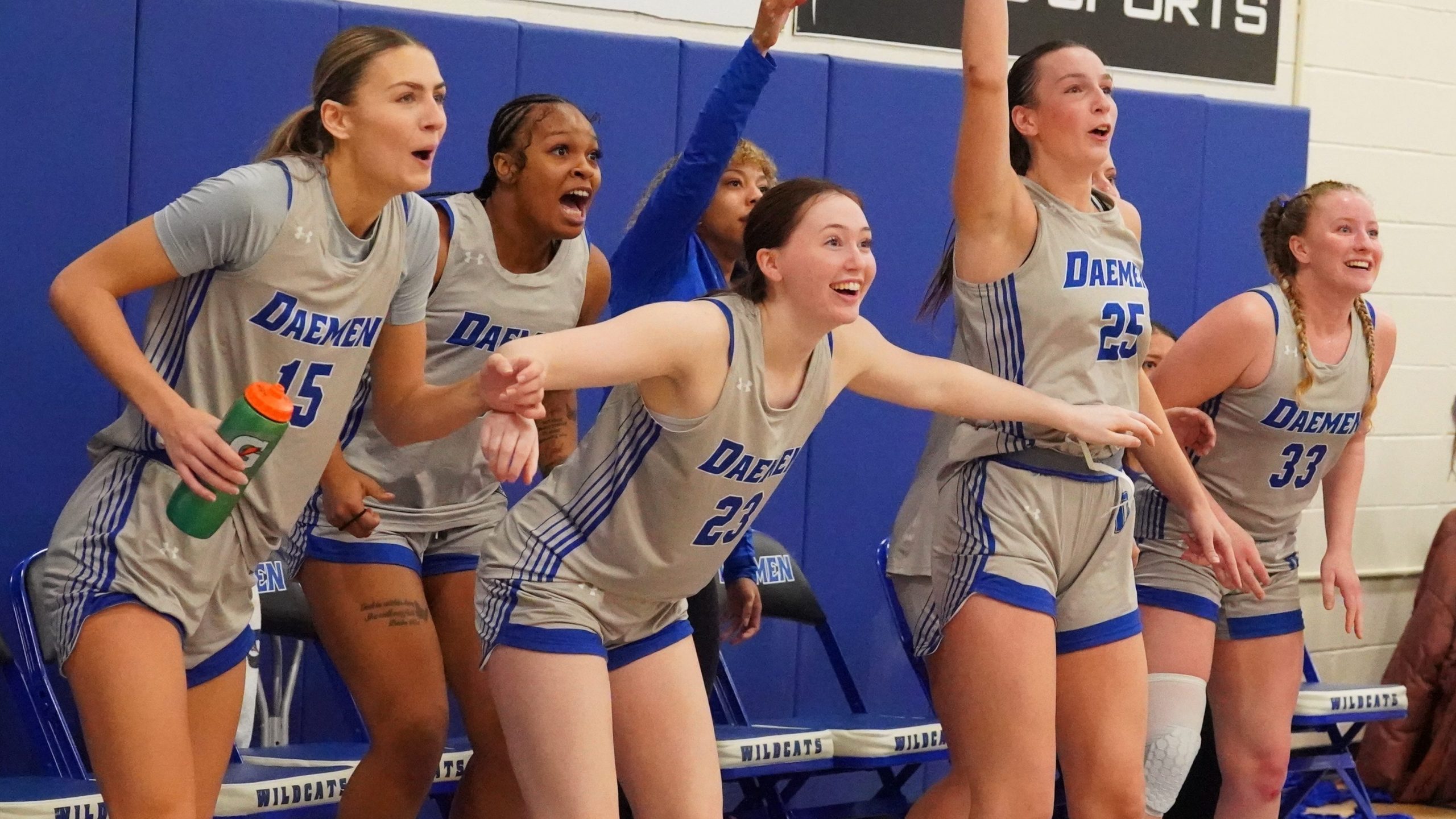 Womens basketball team standing on sideline cheering