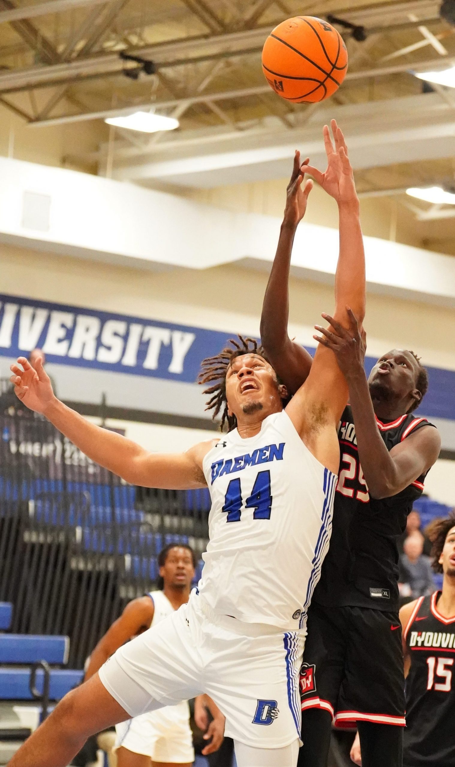 Men's basketball player in front of a player on another team out rebounding them.