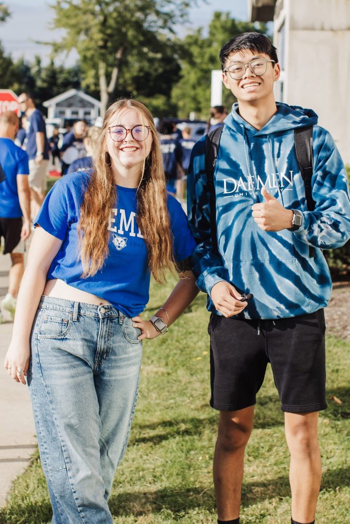 Two students standing together pose in front of Canavan Hall