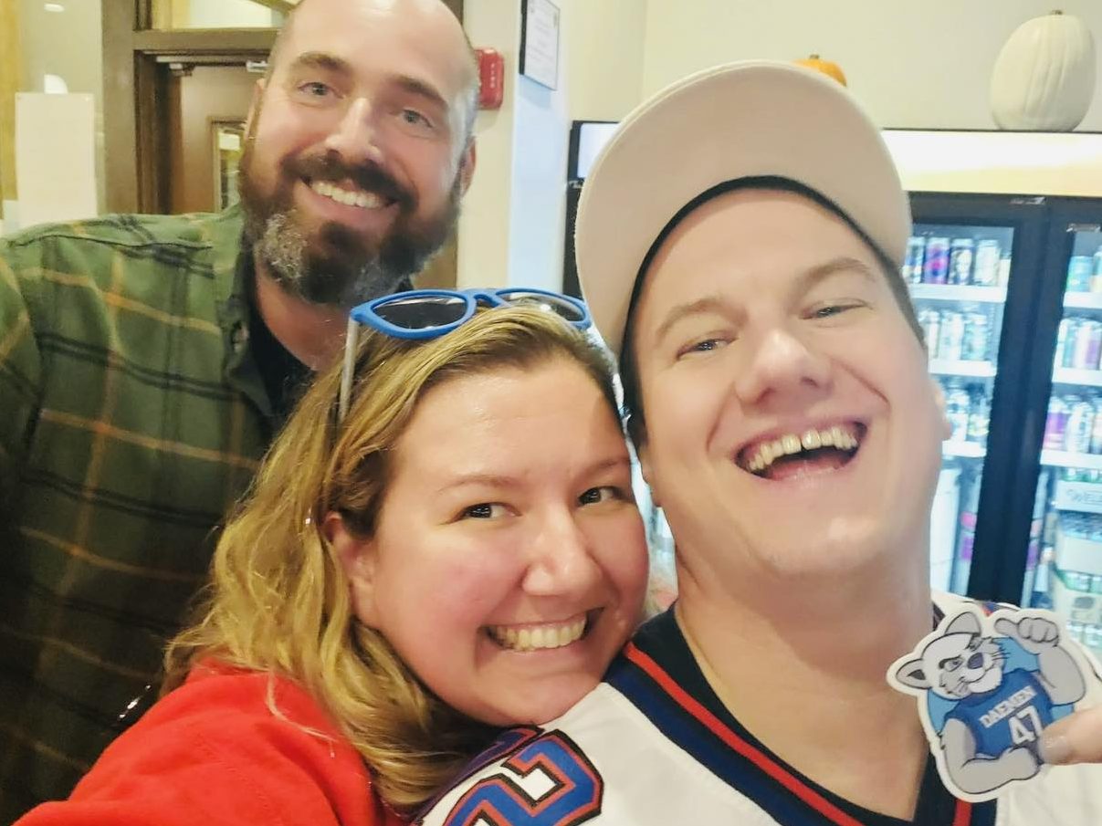 Three adults huddled together, smiling