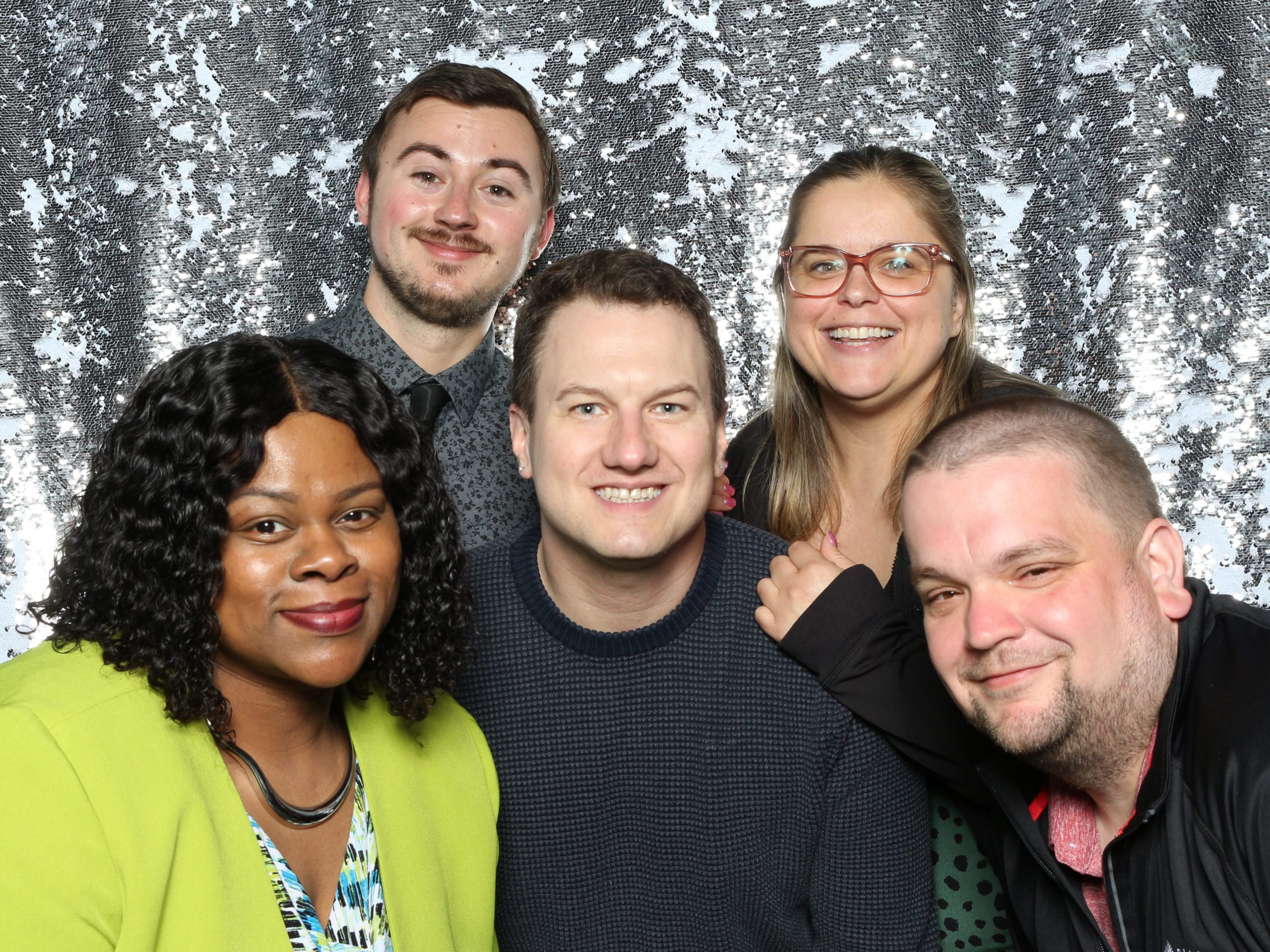 Five people standing together in front of a sparkly backdrop